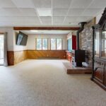 Cozy basement with wooden paneling, fireplace, and sunny windows. Great for relaxation.