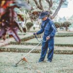 A gardener trims grass in a scenic park setting, focusing on maintenance and landscaping.