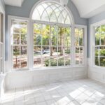 Spacious sunroom with large glass windows offering an outdoor view.