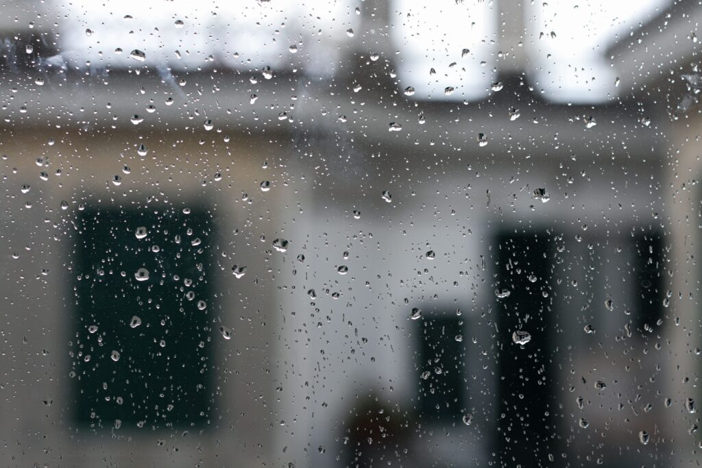 Capture of raindrops on a window with blurred Italian architecture in the background.
